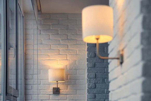 Zwei beleuchtete Wandleuchten an einer weißen Backsteinwand